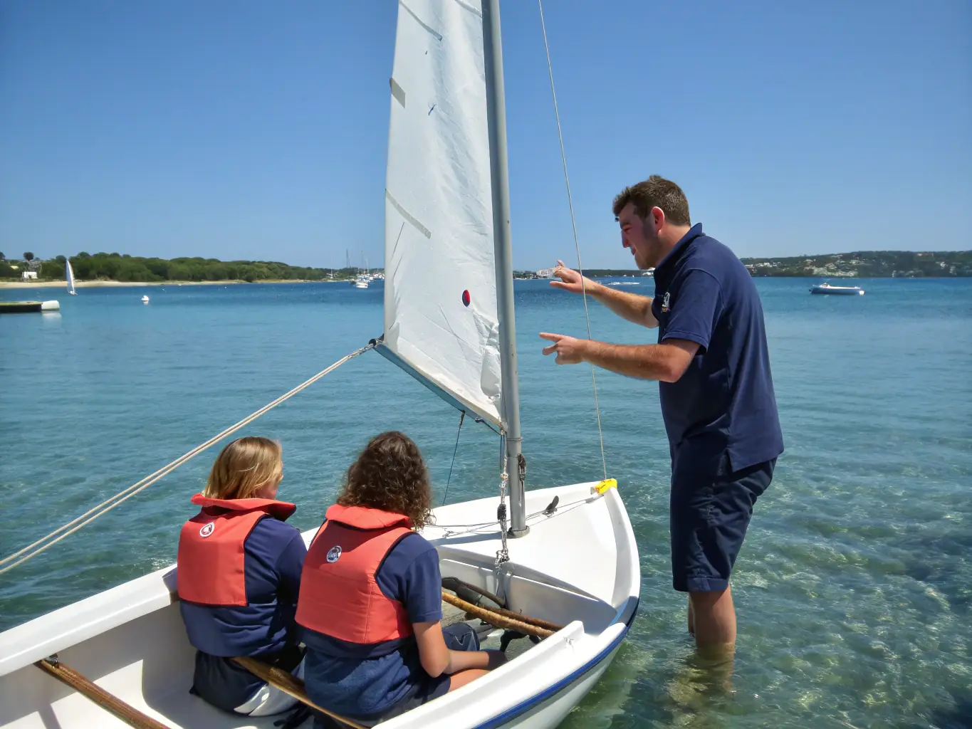 A group of boaters participating in a safety training session on a calm sea, with instructors demonstrating safety procedures.